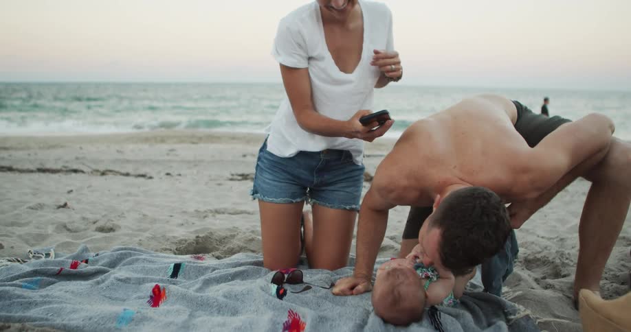 Family capturing happy moments on a smartphone at the beach