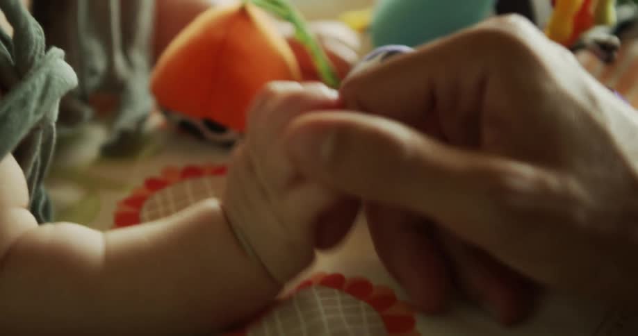 A father hold a babys hand and rubs its skin with his thumb