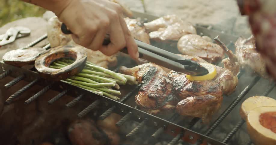 The person is cooking meat and vegetables on the grill