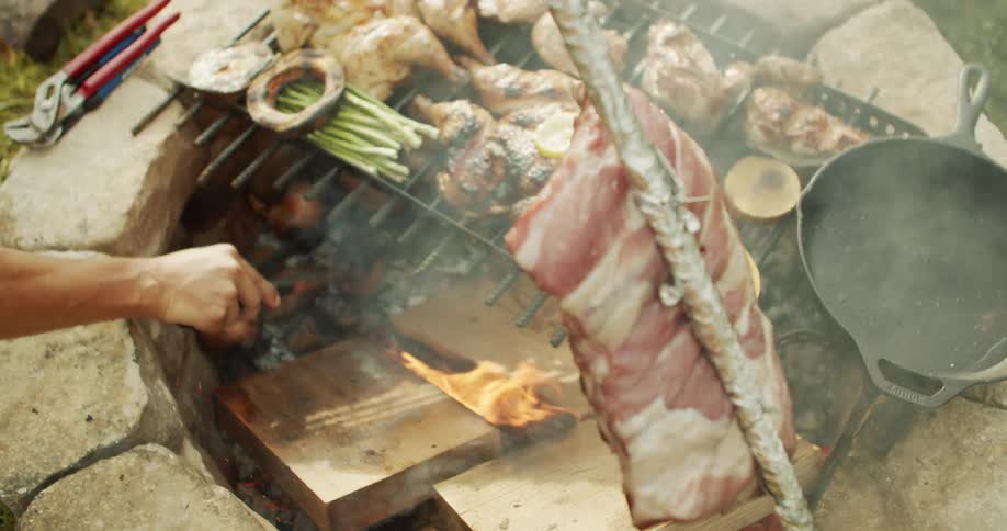 Person grilling meat and vegetables over an open fire pit