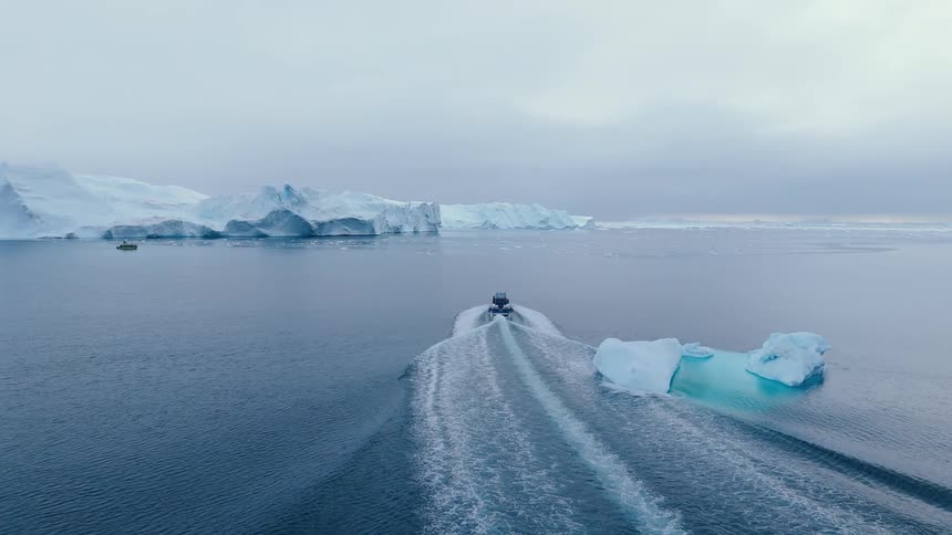 Boat sailing off the arctic coast among icebergs and floating ice