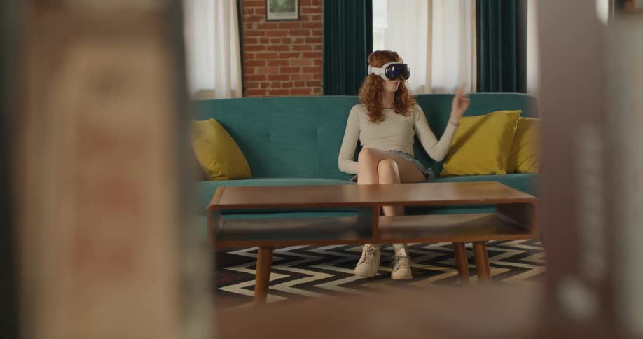 The woman is sitting on her couch using a vr headset