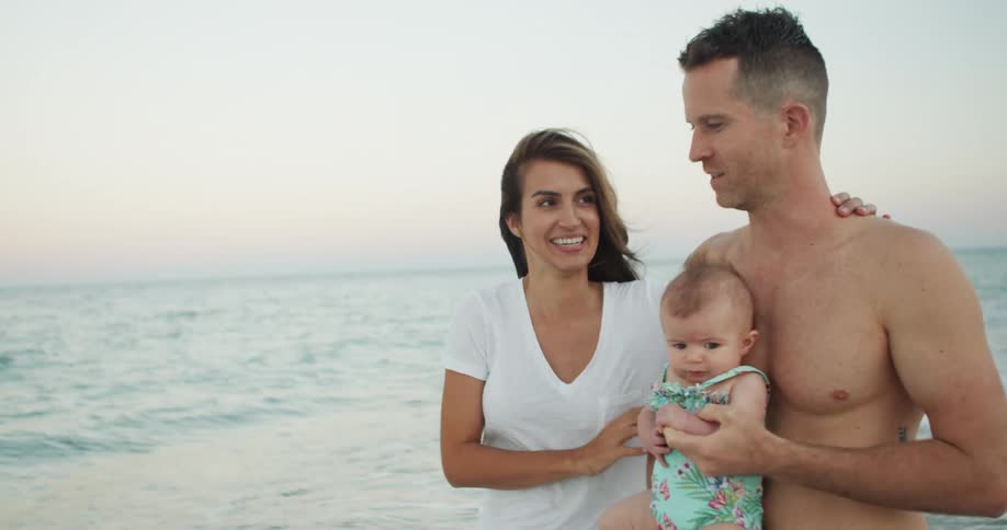 Happy family spending time on sandy beach at dusk