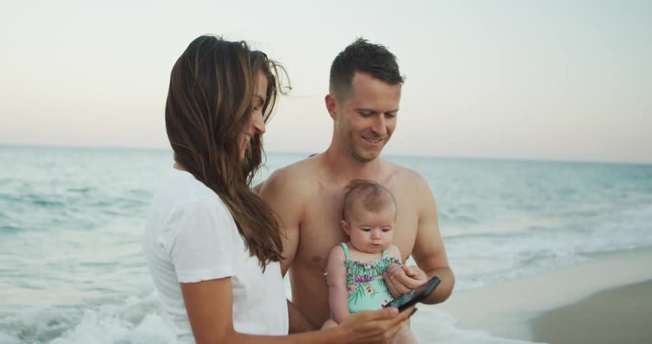 Happy family taking a selfie on the beach at sunset