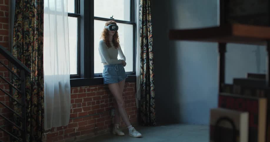 A female teenager using virtual reality goggles while standing in a room during daytime