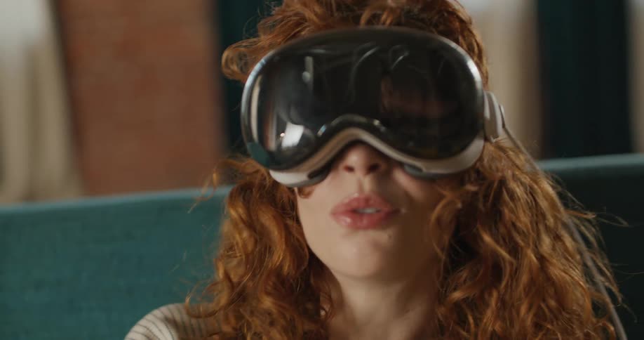 The woman looks off to the side smiling and talking while wearing a vr headset