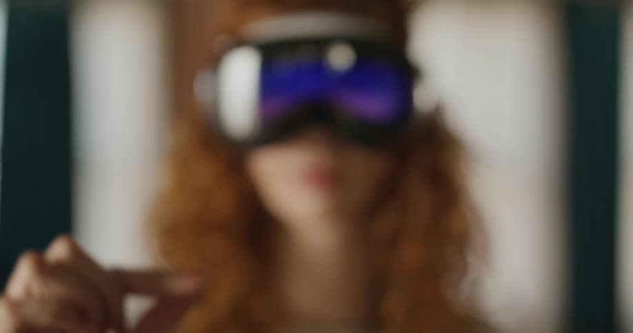 A tight closeup focuses on a persons hand holding their thumb and index finger close together as if measuring a small object which is a gesture often used when interacting with a virtual reality or mixed reality interface in the soft focus bac