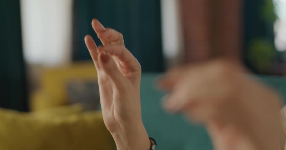 The video is an extreme closeup of a persons hands performing a ritualistic or meditative gesture with the index finger and thumb of each hand gently touching to form a circlethe background is softly blurred with yellow and blue colors drawing
