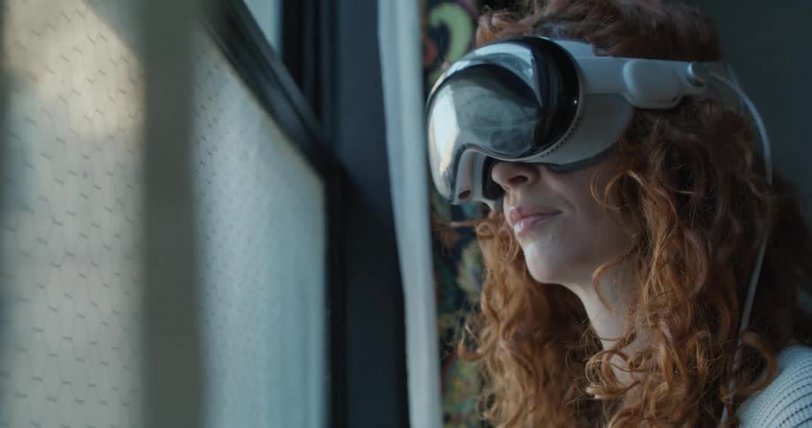 A person with long red hair using a vr headset reaches a hand toward a translucent screen surface with a textured pattern and smiles while manipulating the displayed image