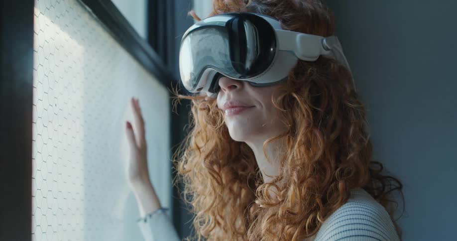 A young man standing in front of a window wearing a virtual reality headset