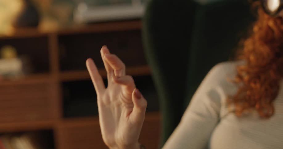 The woman is pointing while she sits using a vr headset