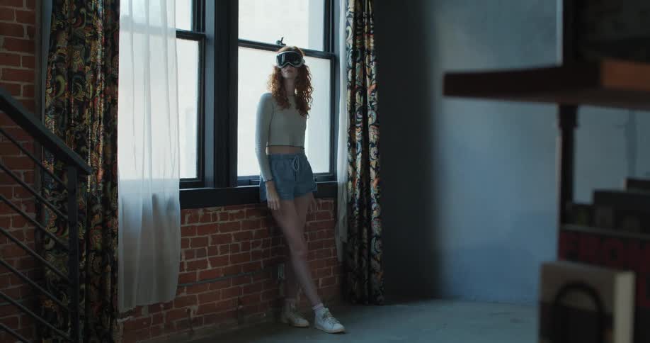 Woman wearing a vr headset stands near a window exploring virtual reality