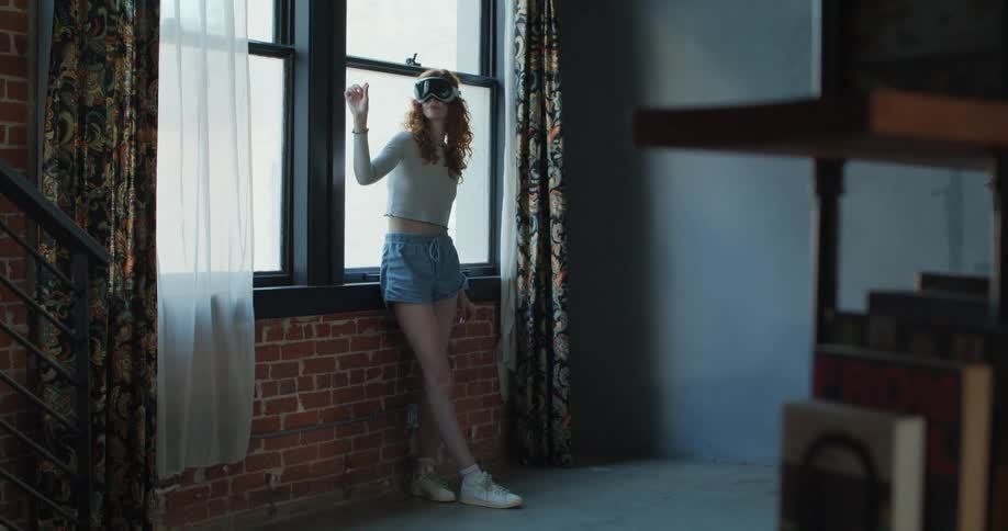 Teenage girl standing near windows wearing a virtual reality headset moving her hands