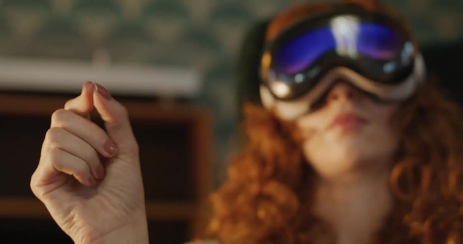 Teenage girl wearing a virtual reality headset holds up her hand and moves her fingers