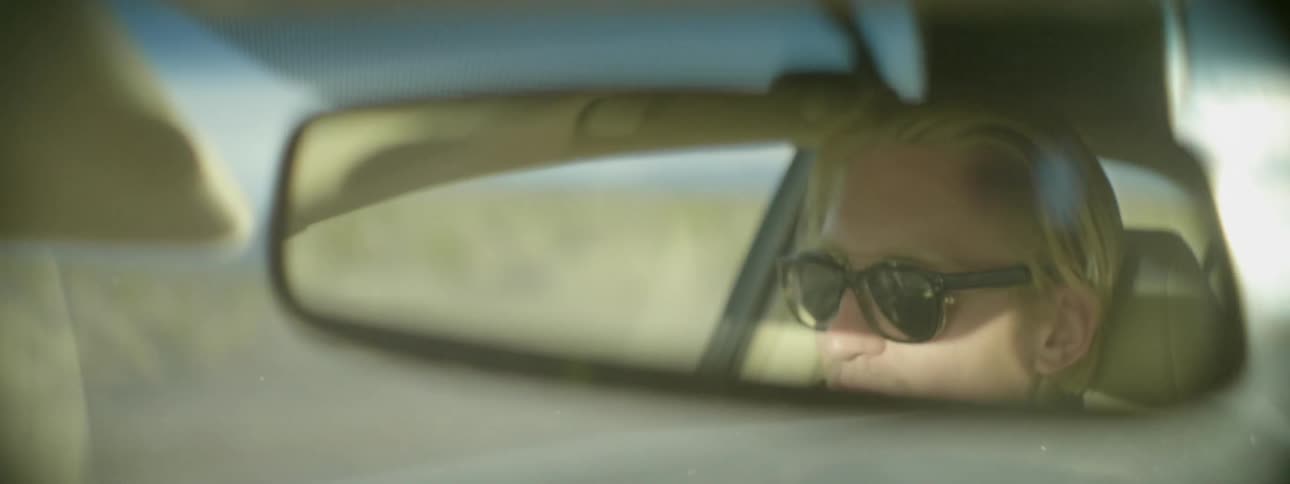 A person in the rearview mirror of their car