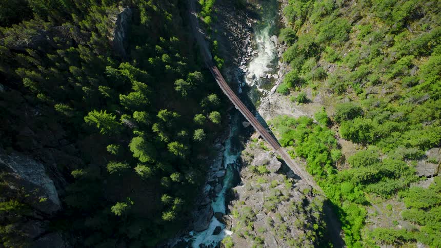 Aerial view of a railroad bridge crossing a forested river canyon