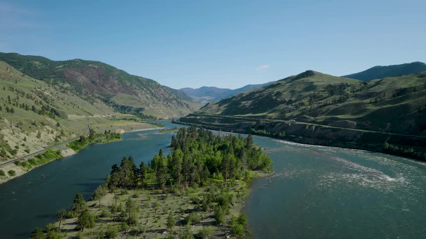 Aerial view of a winding river through green hills under a clear sky