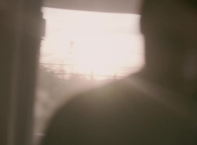 Sunlight glares onto a man drinking a beverage on his porch
