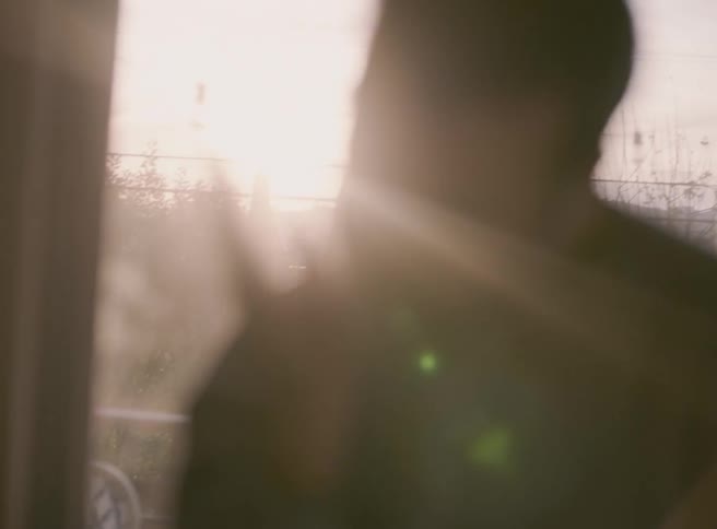 Man pats his own cheek while moving around near the sliding glass doors leading to his balcony