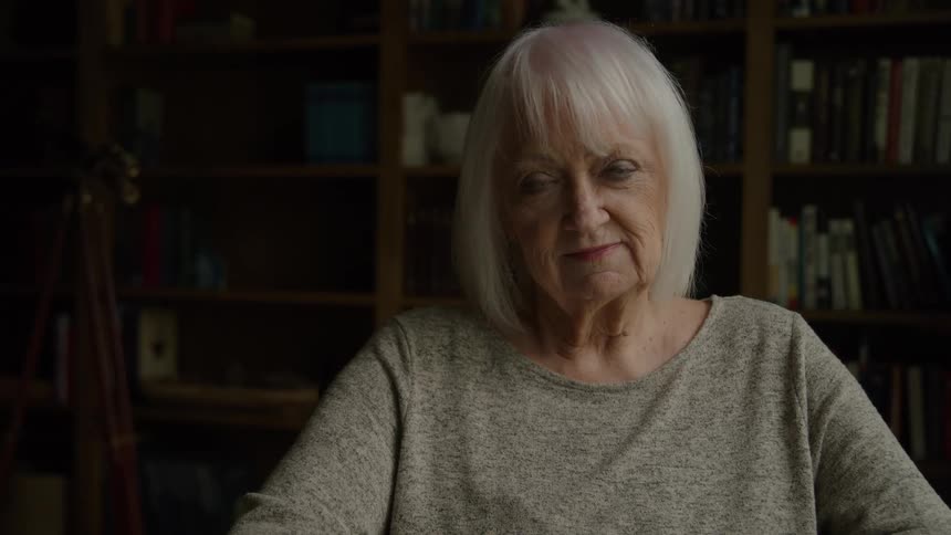 The woman is sitting in front of book cases