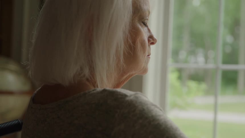 The woman closes her eyes by the window