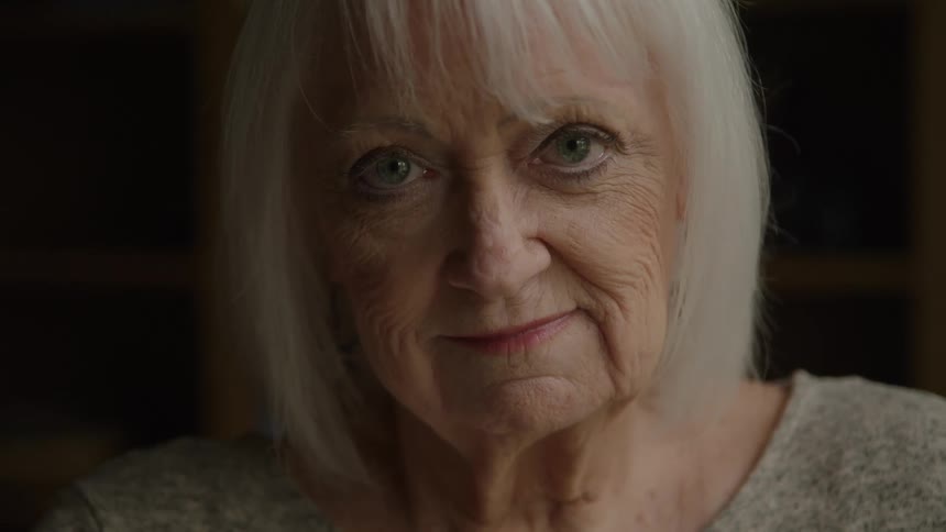 Elderly white haired woman smiles slowly