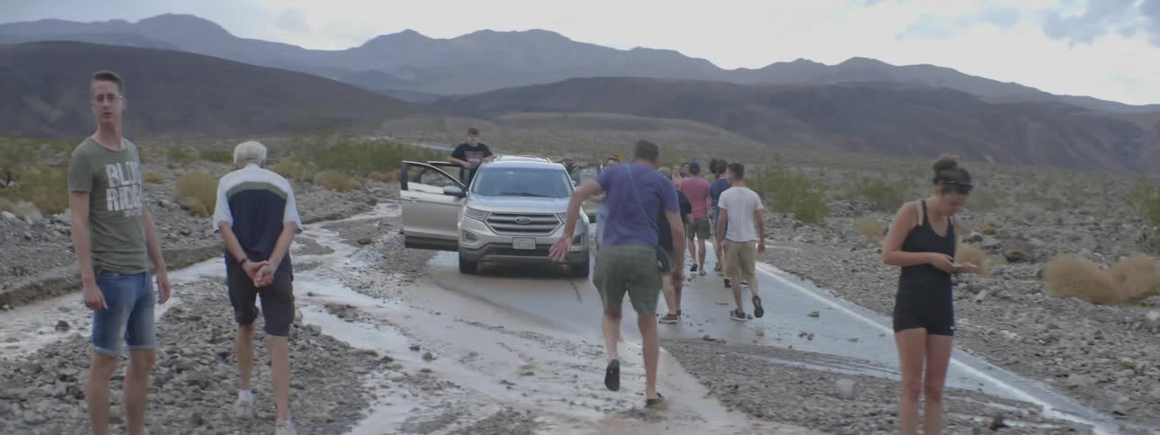 A car is stuck on a washed out road in the wilderness
