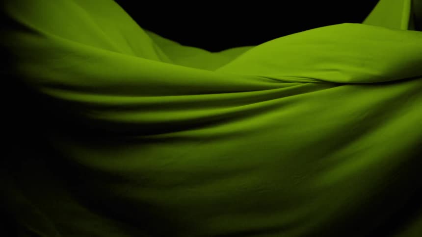 A green fabric moving randomly on a black background
