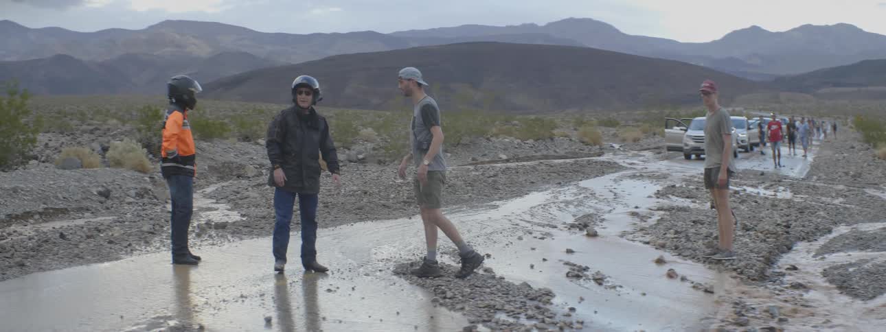 People talk and walk around a mud covered trail