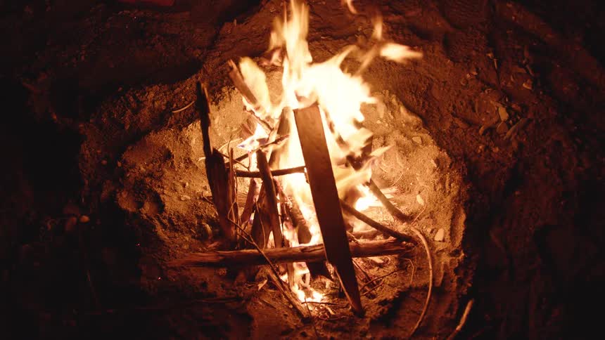 The wood burns in the small campfire