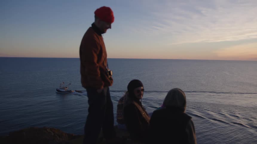 Friends sit by on the cliff by the ocean and talk