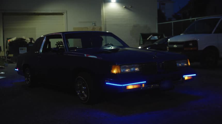 Person sits in a car parked in a parking lot at night