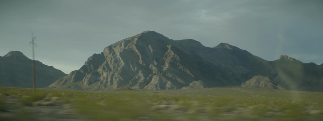A green field leads to tall mountains