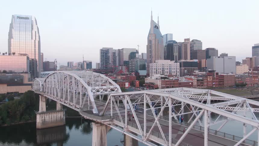 Pedestrians and cyclists cross a river bridge located near downtown