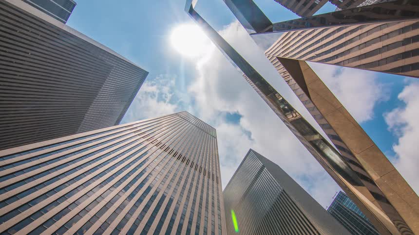 Time lapse of clouds passing above several reflective skyscrapers