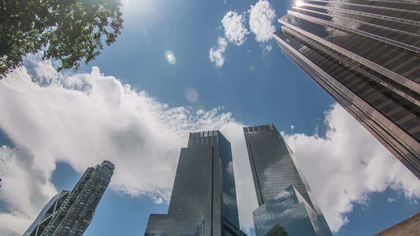 Clouds reflect on the shiny surface of tall modern skyscrapers