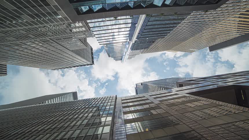 Clouds reflect on the shiny surface of tall modern skyscrapers