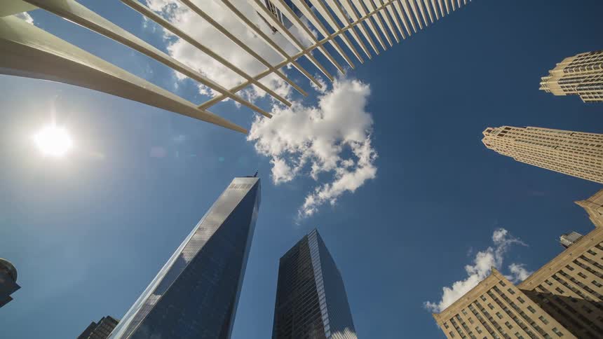 Clouds reflect on the shiny surface of tall modern skyscrapers