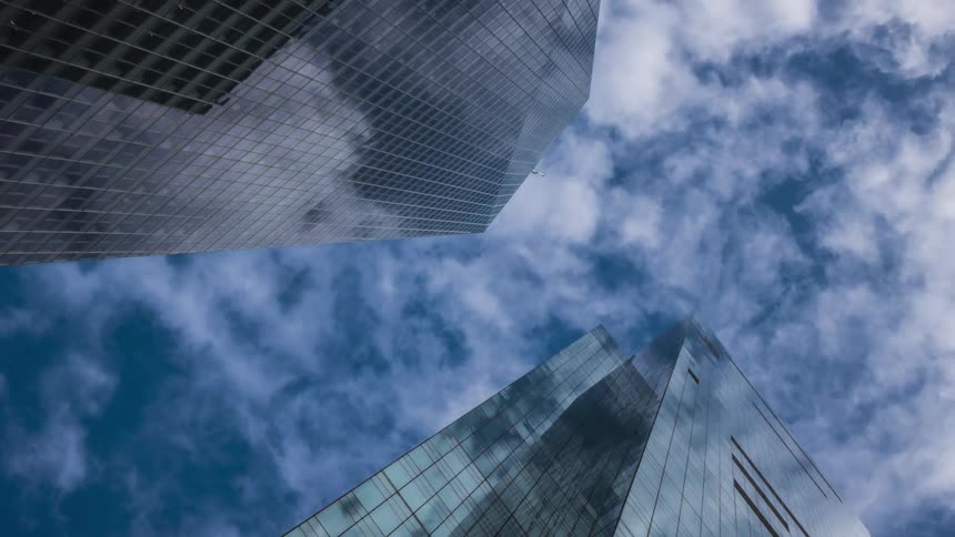 Clouds reflect on the shiny surface of tall modern skyscrapers