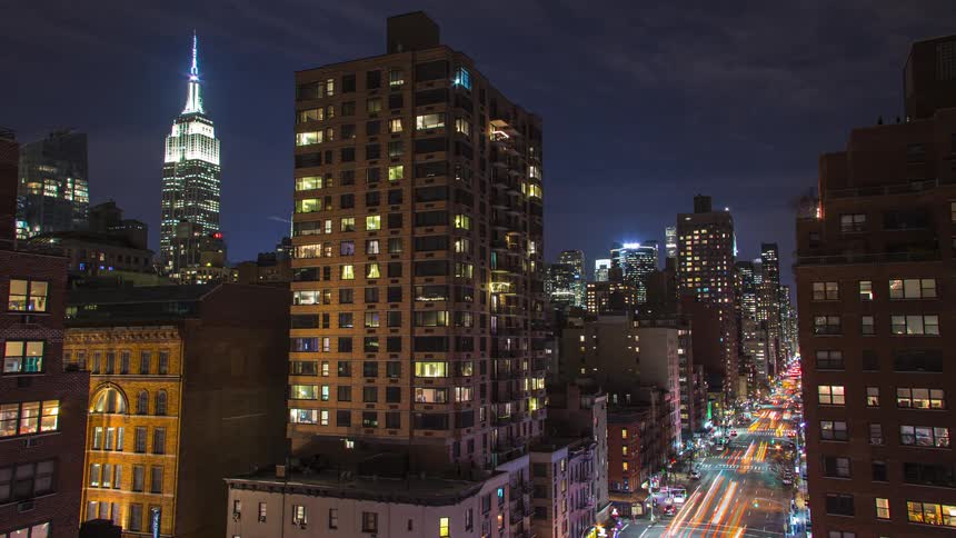 Lights on downtown buildings glow as traffic moves on the street