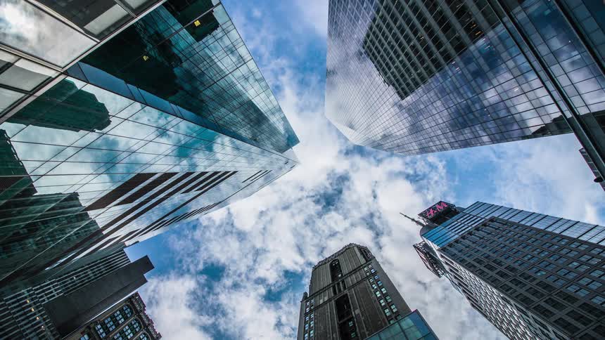 Clouds reflect on the shiny surface of tall modern skyscrapers