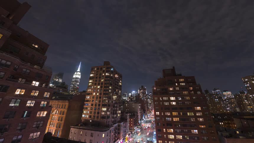 Lights on downtown buildings glow as traffic moves on the street