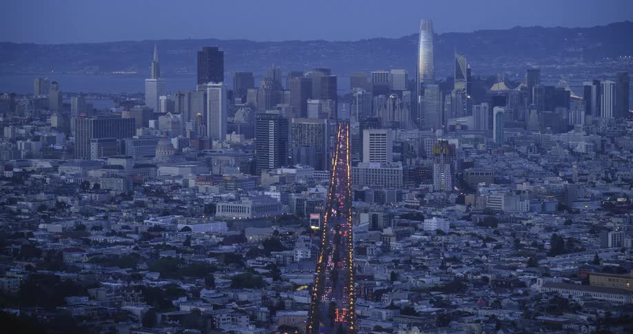 Aerial view of a dense city with a brightly lit road leading to the center