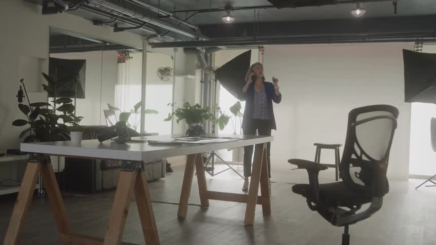 A woman walks around in an office while talking on the phone
