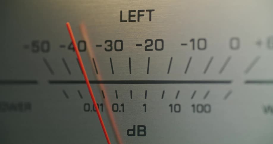 A closeup of an audio meter faceplate shows a red needle oscillating quickly indicating audio level fluctuation on a piece of vintage equipment