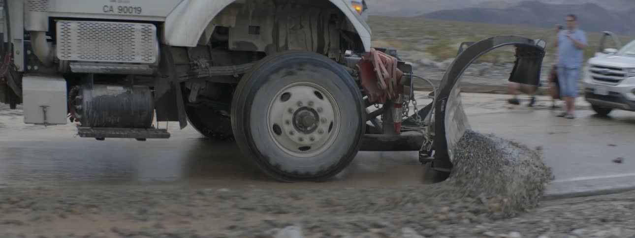 Large truck plowing gravel on a country road