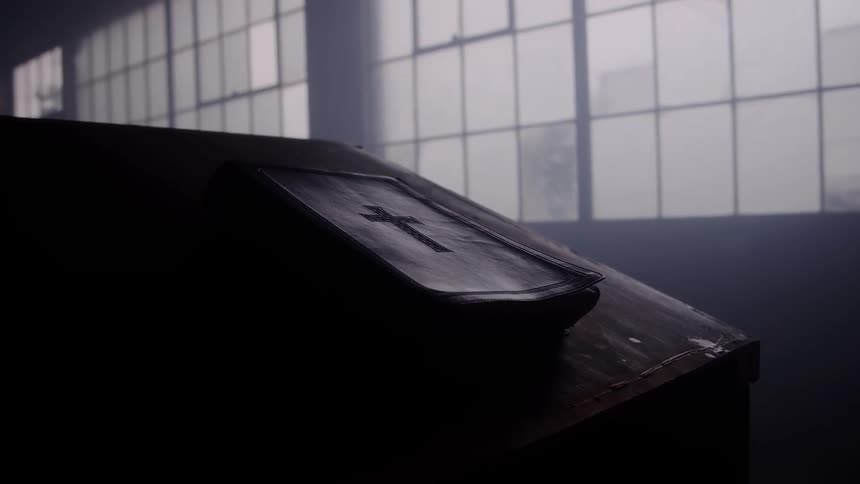 A bible with a cross symbol rests on an altar inside a church at midday