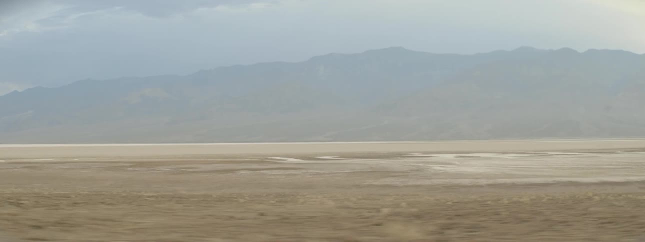 The long barren field leads to a fog covered mountain ahead