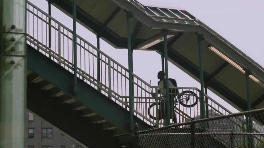 A young man carries his bike up the stairs at the train station
