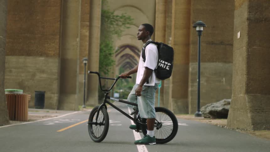 A man stands with his bike in the middle of a path